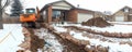 Tractor works at private cottage construction site in winter period. Tractor wheels crunch through snow-covered ground