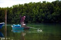 Trad thailand - november26,2017 : unidentified thai villager working on fishery boat against green leaves of mangrove forest