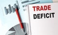TRADE DEFICIT text on a notebook with pen on a chart background Royalty Free Stock Photo
