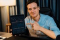 Trader in casual looking at camera stock with pointing laptop. Pecuniary.
