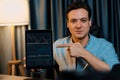Trader in casual looking at camera stock with pointing laptop. Pecuniary.