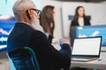 Trader team making stock market analysis conference inside hedge fund office - Focus on senior man face sitting in wheel chair