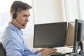 Trader Using Multiple Computer Screens While Communicating Through Headphones Royalty Free Stock Photo