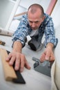 Tradesman laying down linoleum flooring