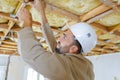 Tradesman using screwdriver on ceiling timbers