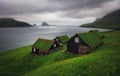 Tradicional faroese grass - covered houses in the village Bour. Drangarnir and Tindholmur sea stacks on background. Vagar island,
