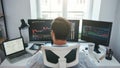 Trading stocks online. Back view of young businessman or trader working with graph and charts on computers at his modern