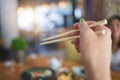 Tradition, bamboo chopsticks and hand of a person eating Japanese food at a restaurant for nutrition. Closeup of a woman Royalty Free Stock Photo