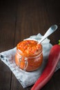 Traditional adjika hot chili pepper sauce paste harissa on wooden board.Tunisia, georgian and arabic cuisine. Vertical orientation