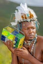 A Traditional African Dressed male with a beaded headdress listens to a beaded radio. Royalty Free Stock Photo