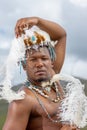 A Traditional African Dressed male with a beaded headdress with ostrich feathers.