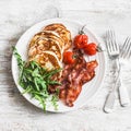 Traditional american breakfast - crispy bacon, pancakes with maple syrup, roasted tomatoes, arugula. On a light background Royalty Free Stock Photo