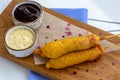 Traditional American street food corn dogs with mustard and ketchup on wooden table. Royalty Free Stock Photo