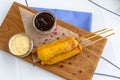 Traditional American street food corn dogs with mustard and ketchup on wooden table. Royalty Free Stock Photo