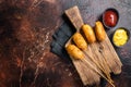 Traditional American street junk food Deep fried corn dogs with mustard and ketchup. Dark background. Top view. Copy Royalty Free Stock Photo