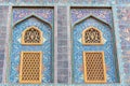 Traditional Arabic mashrabiya window on a tiled wall enclosed with carved wood latticework