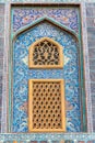 Traditional Arabic mashrabiya window on a tiled wall enclosed with carved wood latticework