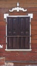 Traditional architecture detail. Brown wooden wall with window closed with wooden shutters with metal fittings and white