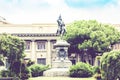 Traditional architecture of Sicily in Italy, typical street of Catania, tree alley, facade of old buildings with monument of King