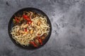 Traditional Asian food - noodles with seafood, salad, red pepper and fried mushrooms are on a gray table. Royalty Free Stock Photo
