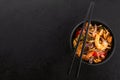 Traditional asian frying noodles with prawns and mussels in a black bowl and chopsticks on a black slate background Royalty Free Stock Photo