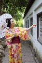 Traditional Asian Japanese beautiful bride Geisha woman wears kimono hold a white red umbrella in a summer nature garden Royalty Free Stock Photo