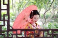 Traditional Asian Japanese beautiful Geisha woman bride wears kimono with red umbrella on hand in a summer nature Royalty Free Stock Photo