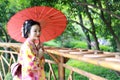 Traditional Asian Japanese beautiful Geisha woman wears kimono bride with a red umbrella in a graden Royalty Free Stock Photo