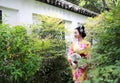 Traditional Asian Japanese beautiful Geisha woman wears kimono with a fan on hand in a summer nature Royalty Free Stock Photo
