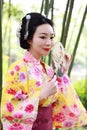 Traditional Asian Japanese beautiful Geisha woman wears kimono hold a fan on hand in a summer graden Royalty Free Stock Photo