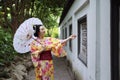 Traditional Asian Japanese beautiful Geisha woman wears kimono hold a white red umbrella in a summer nature garden Royalty Free Stock Photo