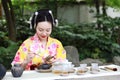 Traditional Asian Japanese beautiful Geisha woman wears kimono show tea art ceremony drink tea in a summer spring outdorr garden