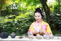 Traditional Asian Japanese beautiful Geisha woman wears kimono show tea art and ceremony in a summer nature