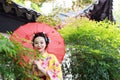 Traditional Asian Japanese beautiful woman bride wears kimono with red umbrella in front of a temple in outdoor spring garden Royalty Free Stock Photo