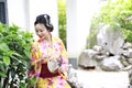 Traditional Asian Japanese beautiful woman wears kimono with fan on hand smiling playing on outdoor spring garden