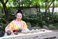 Traditional Asian Japanese beautiful woman wears kimono show tea art and ceremony sit on stone bench in outdoor spring garden Royalty Free Stock Photo