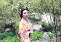 Traditional Asian Japanese beautiful woman wears kimono in a spring garden park stand by bamboo enjoy free time Royalty Free Stock Photo