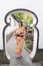 Traditional Asian Japanese beautiful woman wears kimono in a spring garden park stand by bamboo enjoy free time fan Royalty Free Stock Photo