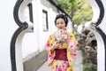 Traditional Asian Japanese beautiful woman wears kimono in a spring garden park stand by bamboo enjoy free time fan Royalty Free Stock Photo