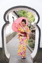 Traditional Asian Japanese beautiful woman wears kimono in a spring garden park stand by bamboo enjoy free time fan umbrella