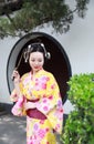 Traditional Asian Japanese woman bride Geisha wearing kimono play in a graden hold a fan Royalty Free Stock Photo