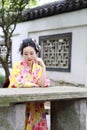 Traditional Asian Japanese woman in a outdoor garden sit on a stone bench