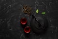 Traditional Asian tea ceremony. Black metal teapot, tea cups, dry tea on a black stone background. Top view, flat lay Royalty Free Stock Photo