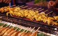 Traditional Asian Thai street food and fast food, delicious grilled squid calamari skewers in food market stall background.