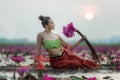 Traditional asian woman harvest red lotus flower in nature river,