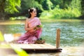 Traditional asian woman Thai dress sitting and relax in wood bridge nature river.