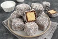 Traditional Australian Lamington cake in chocolate glaze and coconut flakes on a plate on a gray concrete background