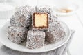 Traditional Australian Lamington cake in chocolate glaze and coconut flakes on a white plate on a white wooden background Royalty Free Stock Photo