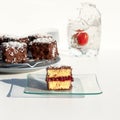 Traditional Australian lamington cakes with strawberry jam, chocolate and coconut. Against of a glass of water, a splash Royalty Free Stock Photo
