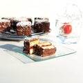 Traditional Australian lamington cakes with strawberry jam, chocolate and coconut. Against of a glass of water, a splash Royalty Free Stock Photo